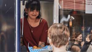 Catering truck worker hands food to customer