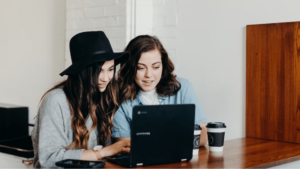 Two event creators look at a laptop screen together