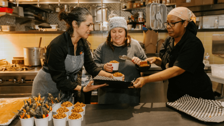 Three people preparing food at an event