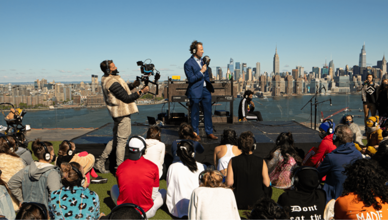 Audience sits on roof top watching a man