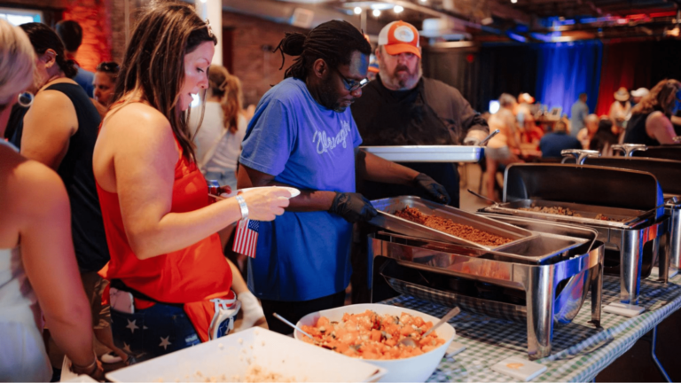 Event staff change out trays of food in a buffet line