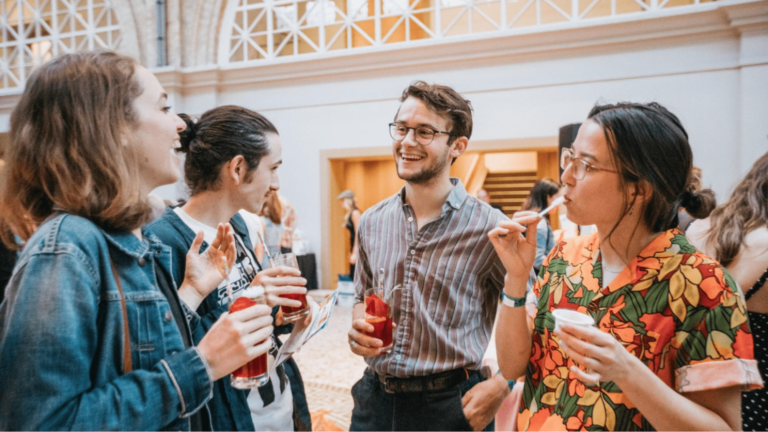 Cocktail party guests laugh and enjoy drinks