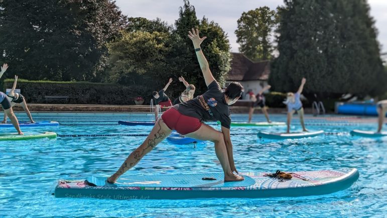 A woman on a stand up paddle board doing a yoga pose