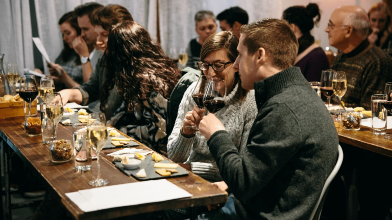 A group of people seated at a table tasting wine and cheese